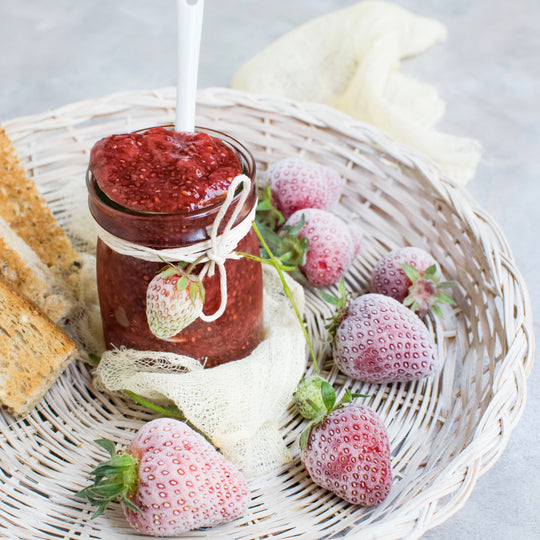 Jam  inside mason jar with strawberries around it